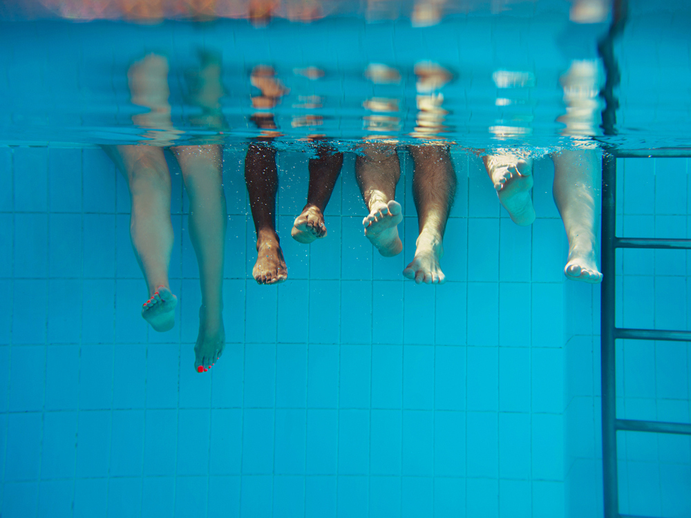 Four,People,Legs,Underwater,In,The,Swimming,Pool.,Party.,Summer.